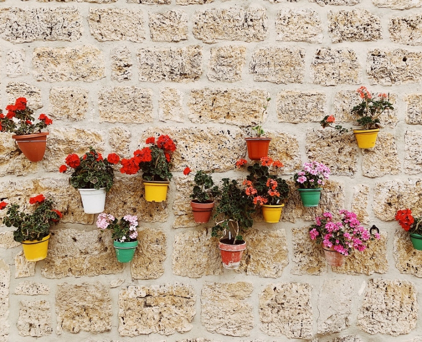 Vrolijk gekleurde bloempotten aan stenen muur